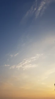 A wide-open sky at dawn with soft clouds drifting, capturing the vastness of space and air