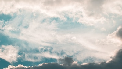 Clouds move across a vibrant blue sky, creating a dynamic and dreamy atmosphere with soft, swirling patterns.
