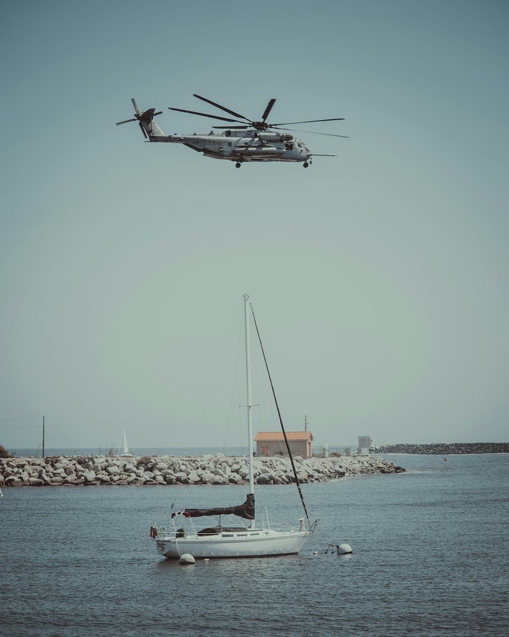 white helicopter flying over anchored yacht
