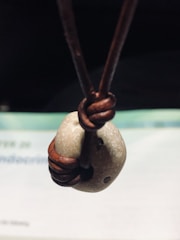 Artisan hand knotting macramé threads around a natural stone.