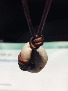 Man outdoors wearing a leather cord necklace with rustic metal details