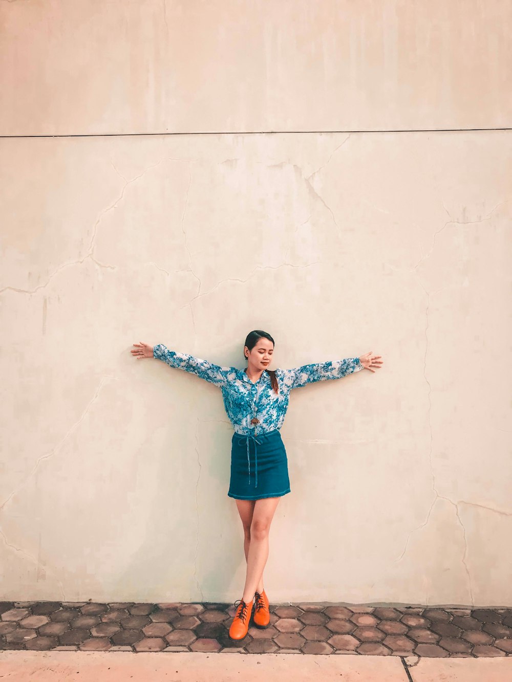 unknown person leaning on white wall outdoors