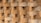 A close-up view of a stack of clay bricks arranged in an interlocking pattern, showcasing their rough texture and earthen color.