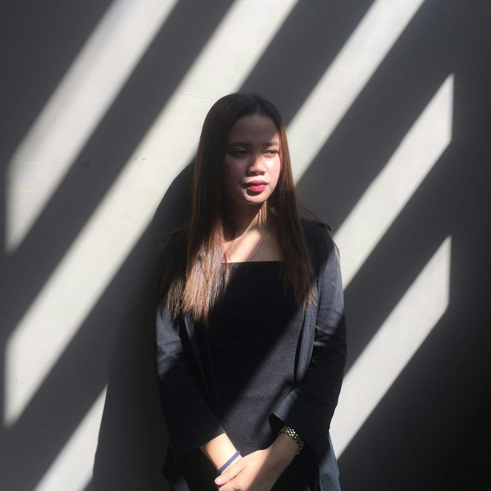 woman wearing black dress leaning on wall