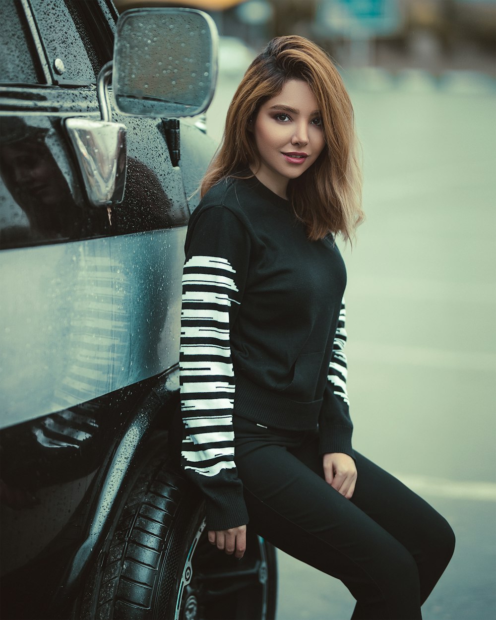 woman seated by a black and white vehicle