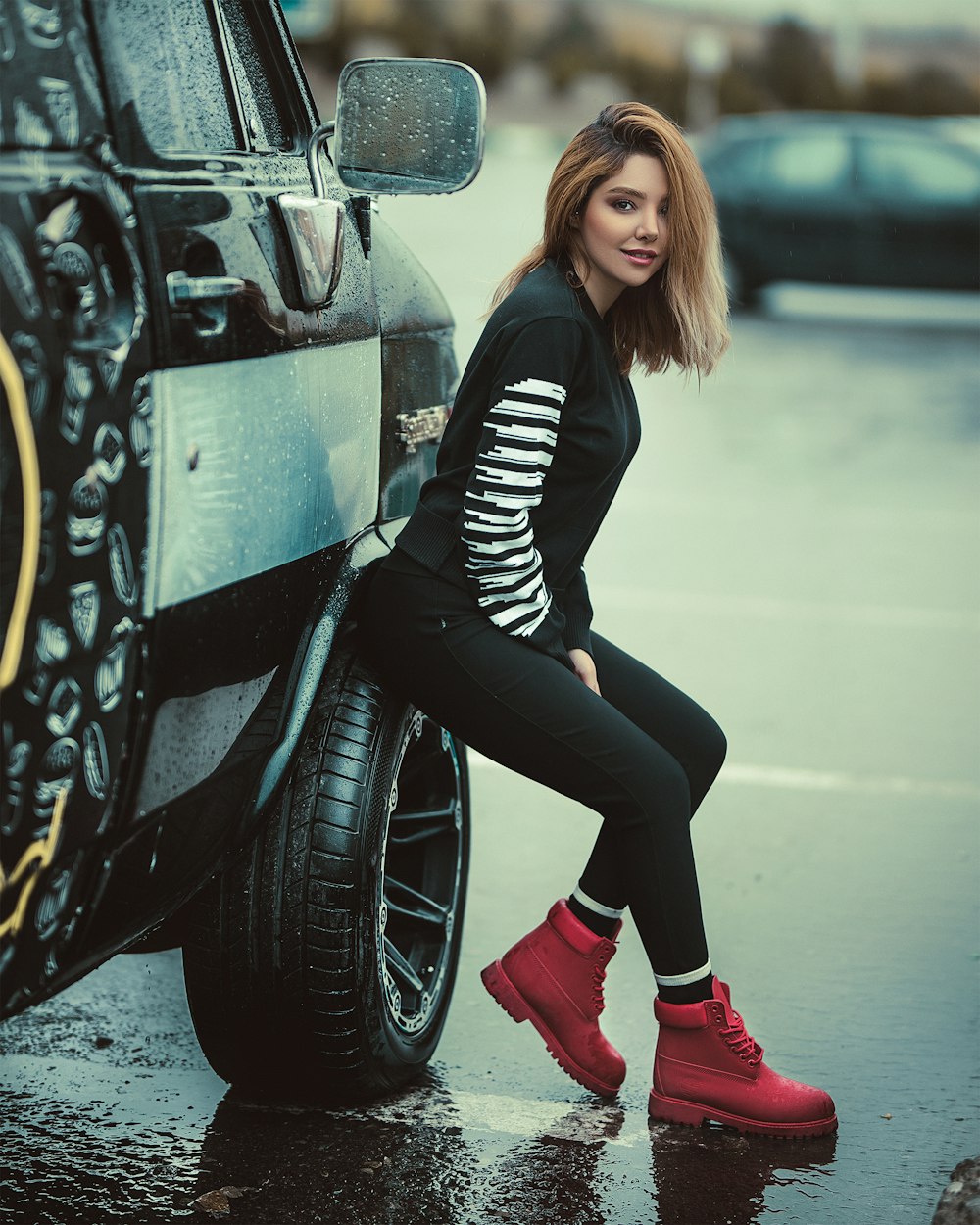 smiling woman wearing black leggings sitting on vehicle wheel