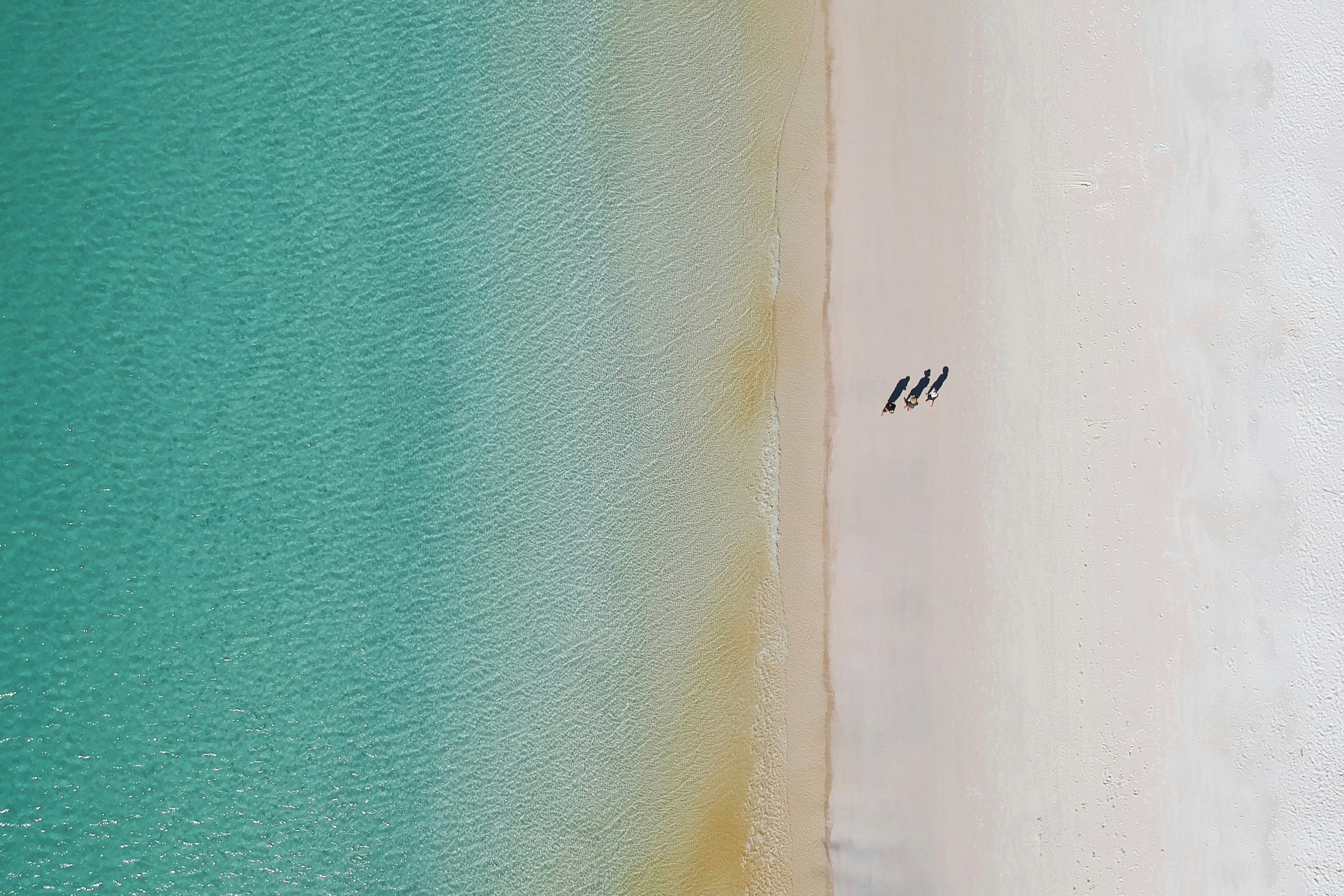 Zwei Personen, die an einem Strand neben dem Meer spazieren gehen