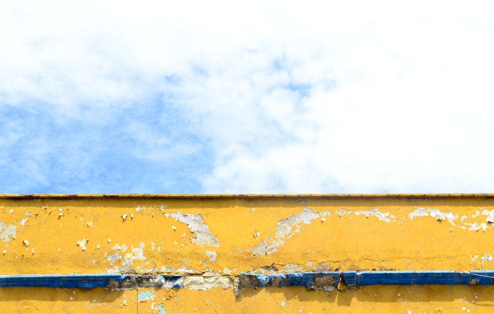 a yellow and blue wall with a sky in the background