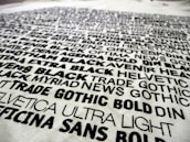 A collection of various fonts and typefaces printed in black ink on a white background, with names like Helvetica, Trade Gothic, and DIN. The text is bold and arranged in a scattered manner, showcasing different font weights and styles.