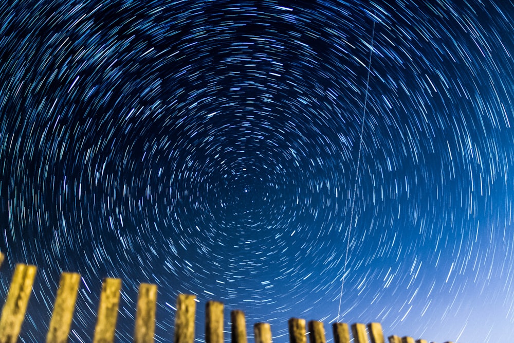 a star trail is seen in the sky above a fence