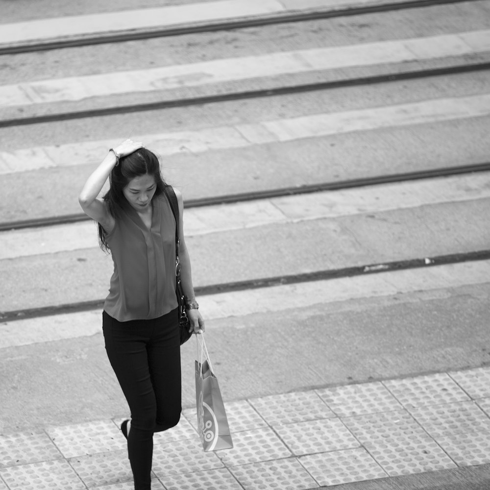 gray scale photo of woman walking on pedestrian lane