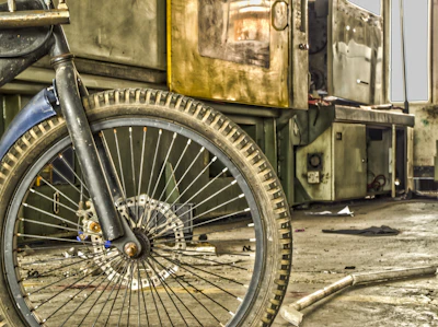 A workshop scene showing hands repairing a bicycle wheel with tools and bike parts scattered around.