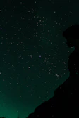 A mysterious silhouette contemplating under a starry night sky with subtle purple hues.