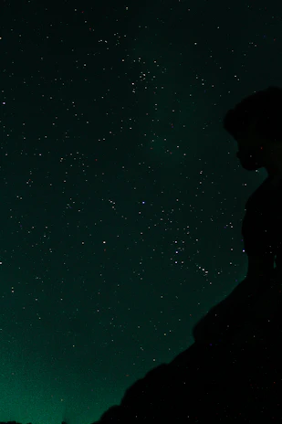 A thoughtful person looking up at a starry sky symbolizing the search for God.