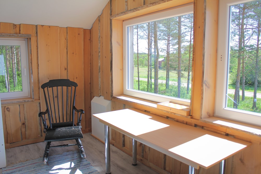 black wooden rocking chair beside glass window