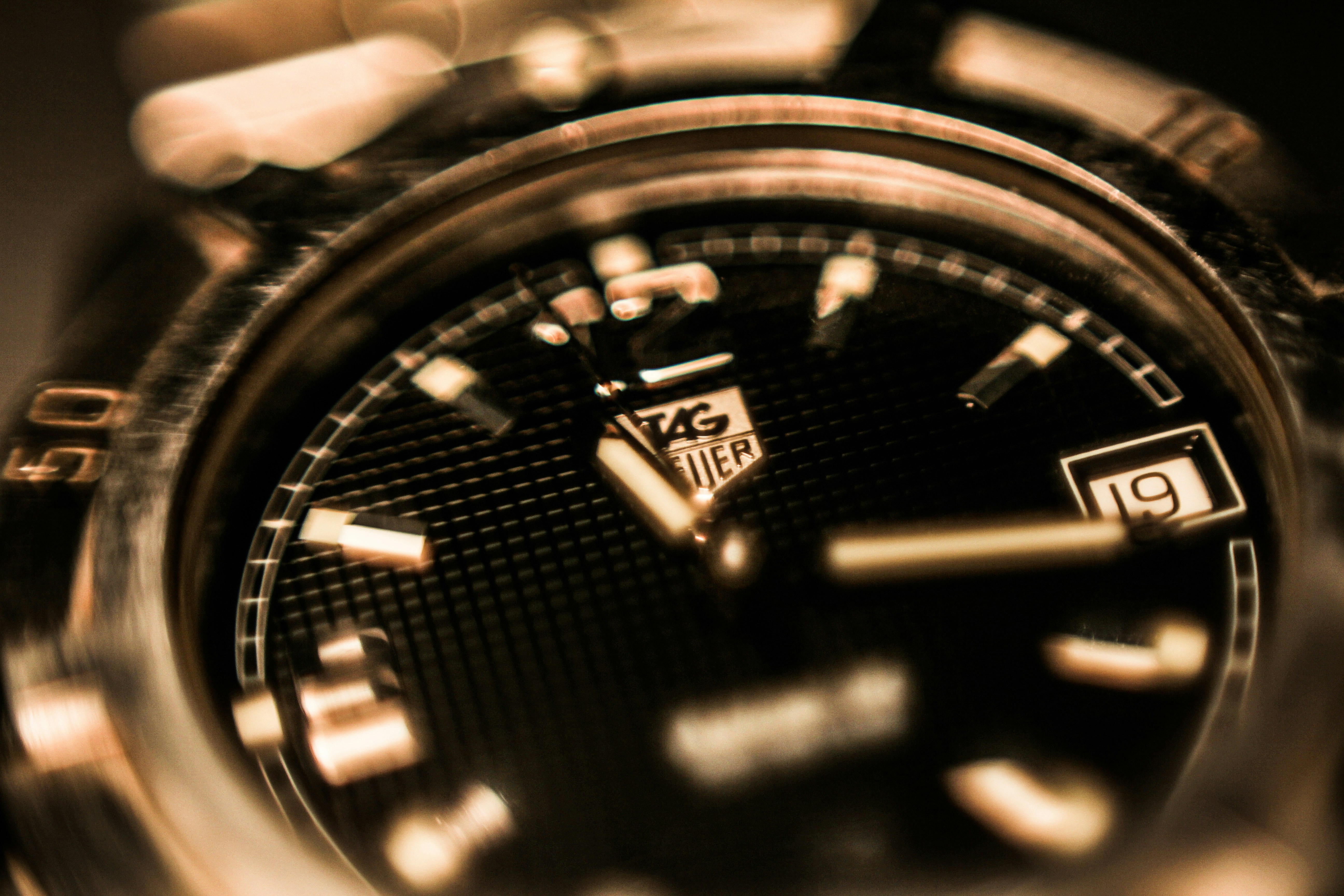 Watch dial close-up with intricate guilloché pattern, near-black background, gold indices