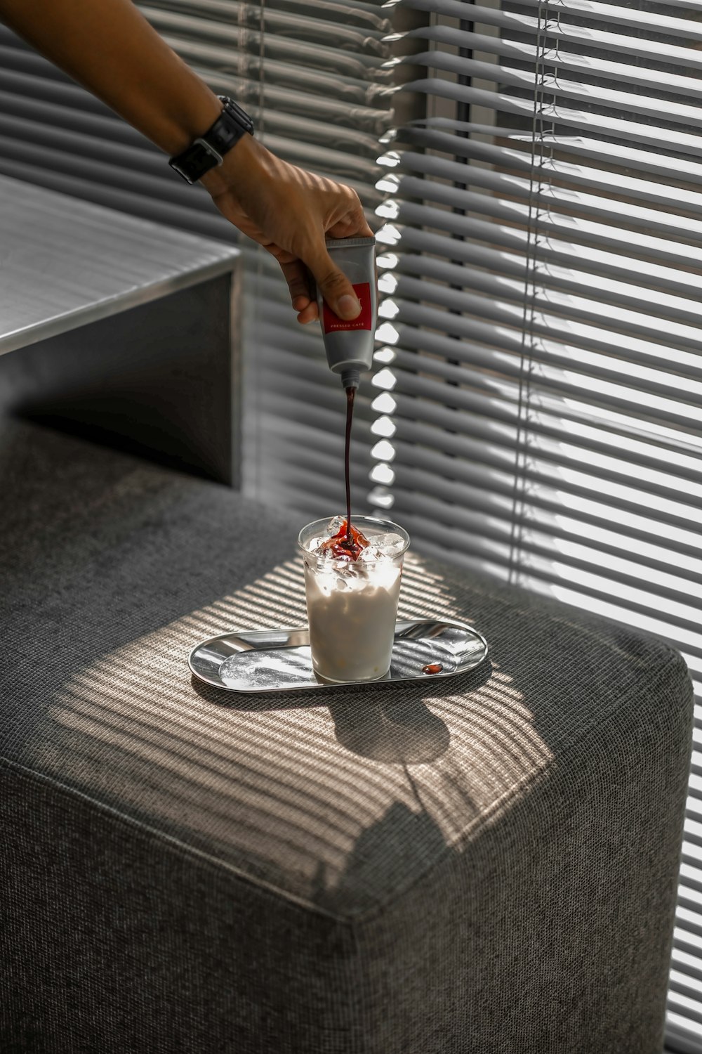 man puts red paste on glass of white beverage