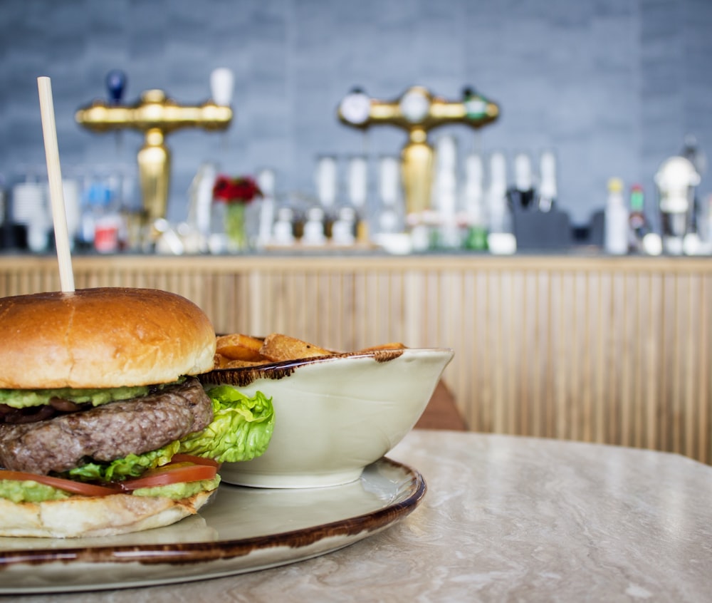 hamburger beside round white bowl