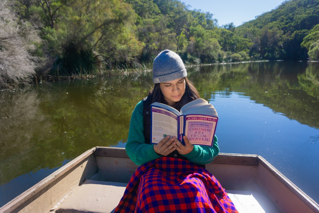 woman sitting on boat while reading book during daytime