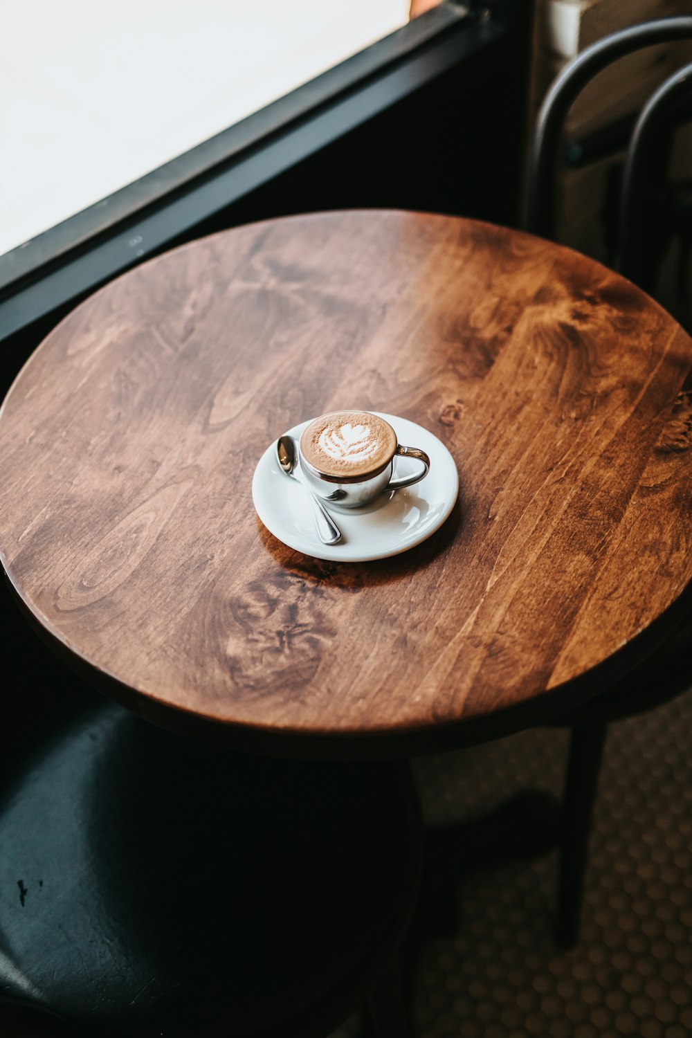 latte in cup on round brown wooden table