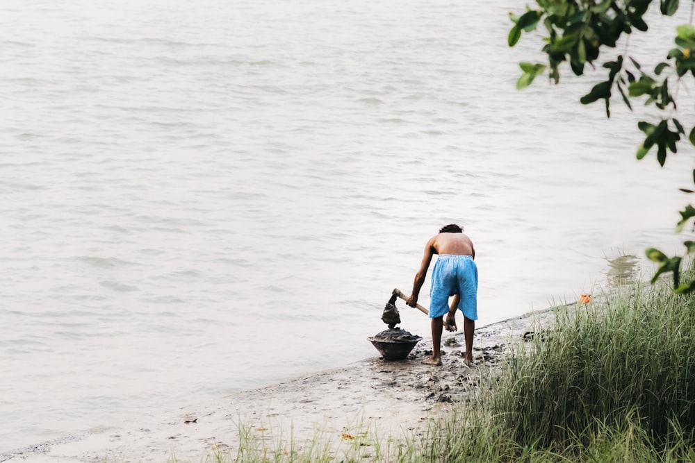 man digging on shoreline using draw hoe