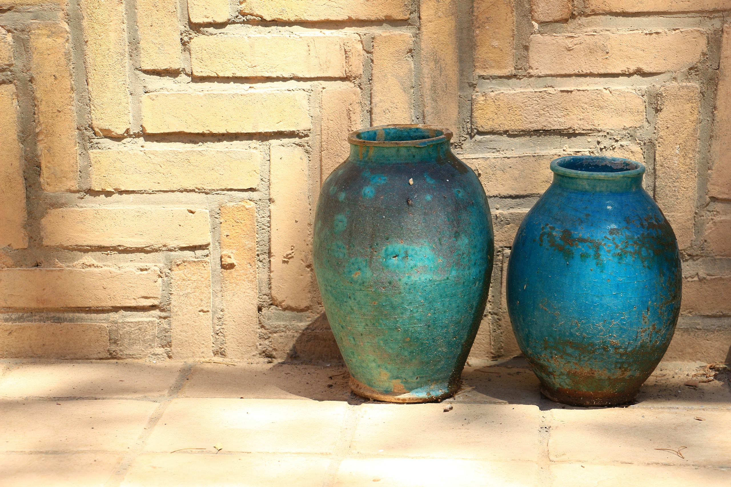 two blue ceramic vases near brown concrete wall