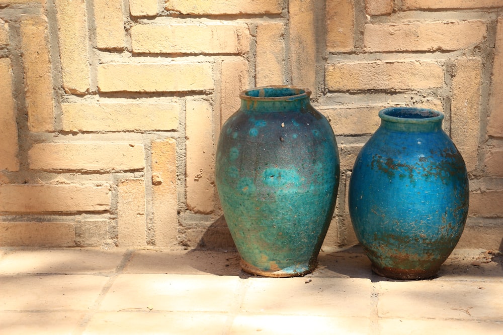 two blue ceramic vases near brown concrete wall