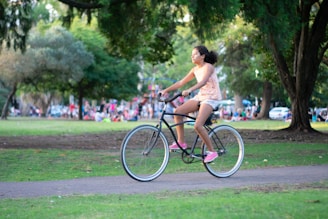 A group of young people riding bicycles through a city park on a sunny day.