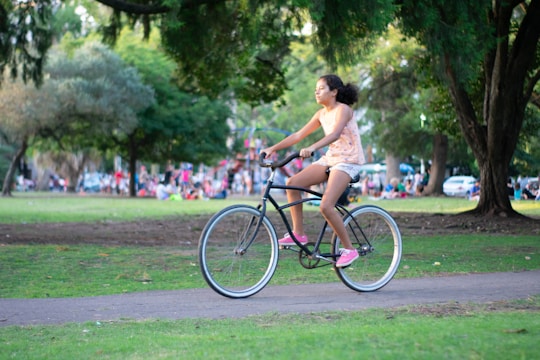 A group of young people riding bicycles through a city park on a sunny day.