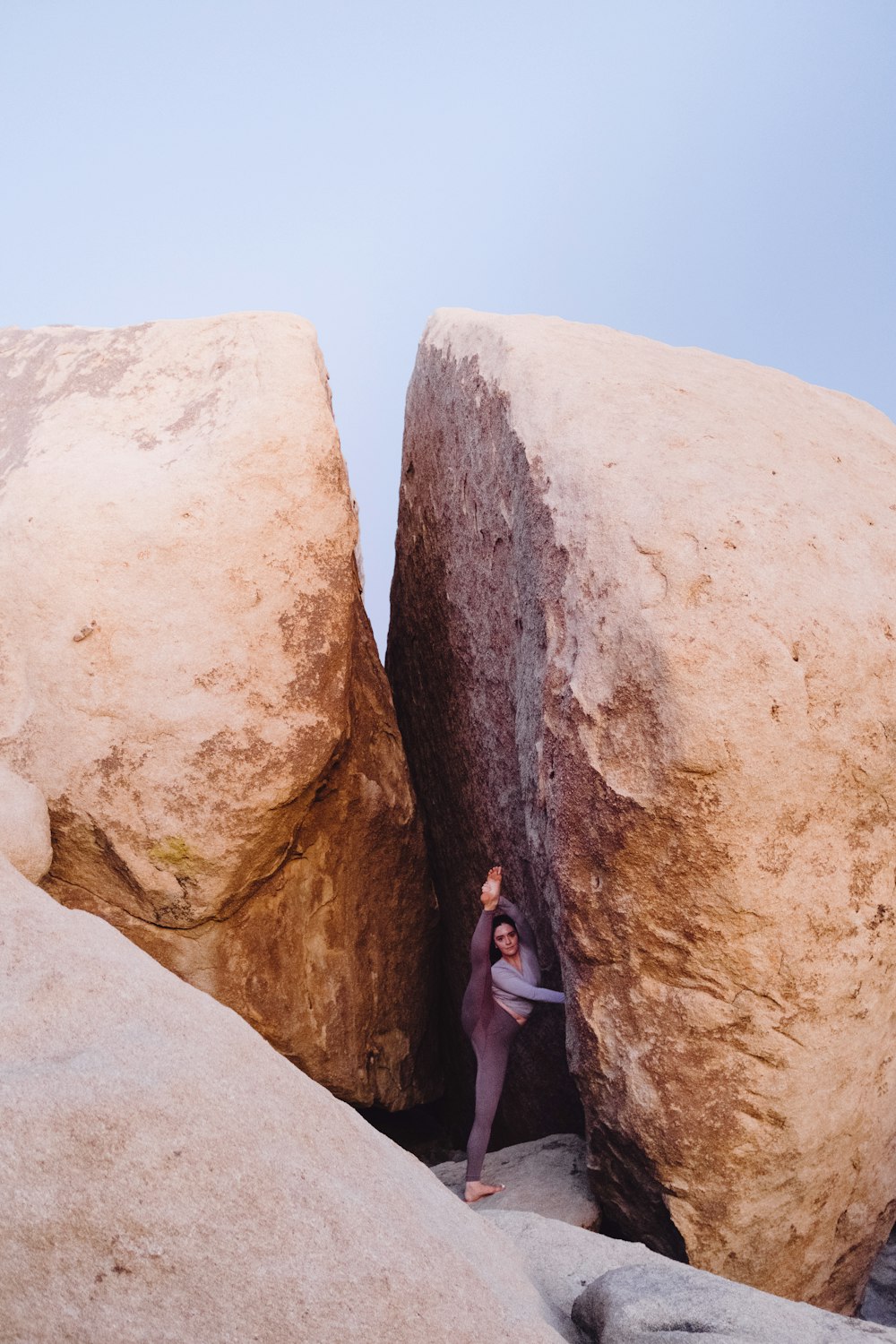 woman wearing grey shirt standing beside rock