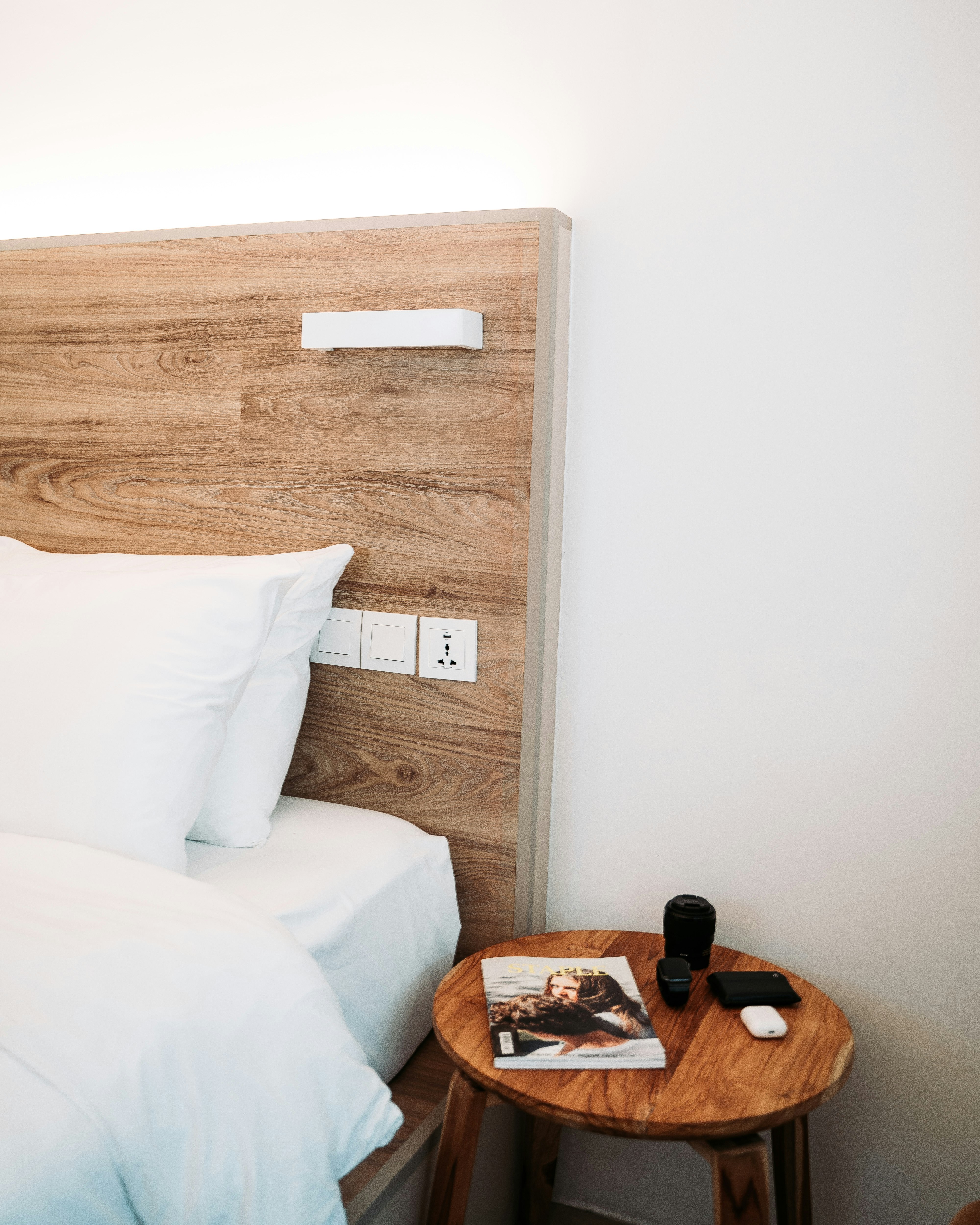 brown wooden headboard and round brown wooden end table