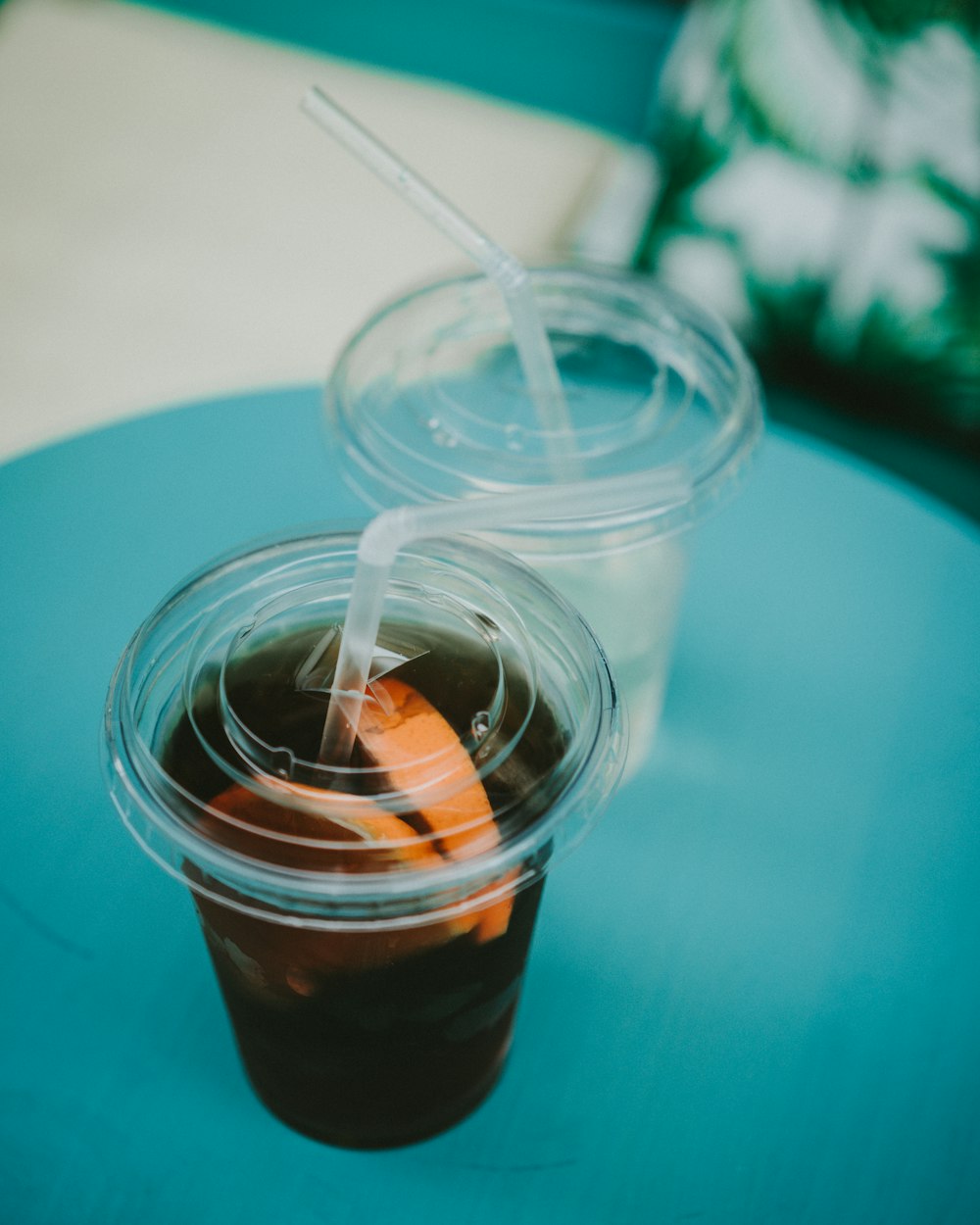 two clear plastic disposable cup with black liquid