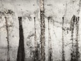 A textured concrete wall with vertical streaks and patterns from stains or weathering, giving it an old and industrial appearance.