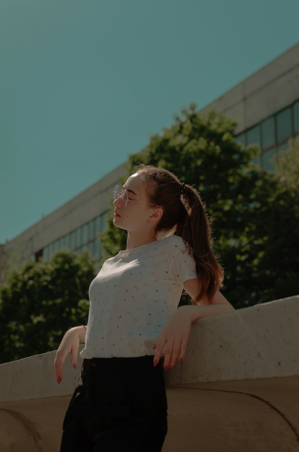 woman leaning on beige concrete rail while closing her eyes during daytime