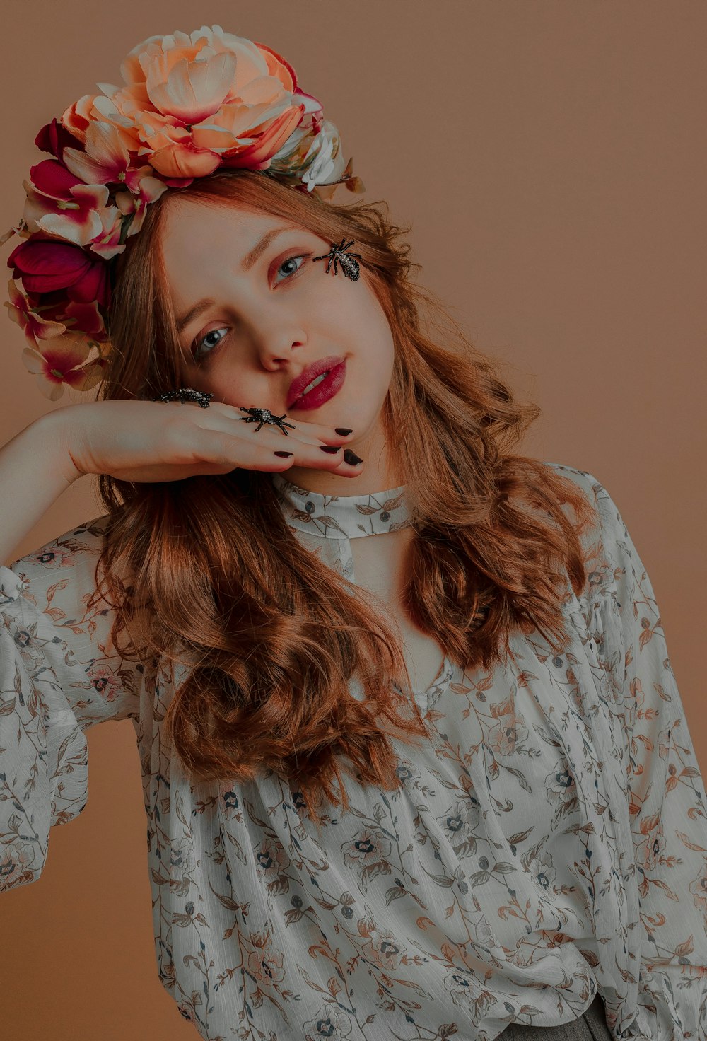 woman wearing white and brown floral dress showing black spider ring