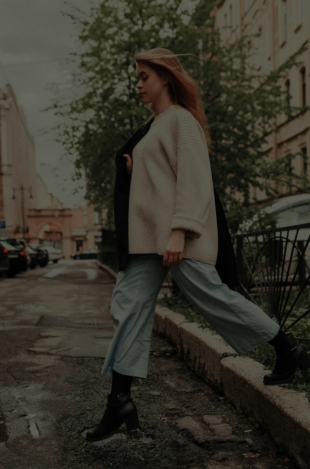 woman in white long-sleeved crew-neck shirt crossing the street