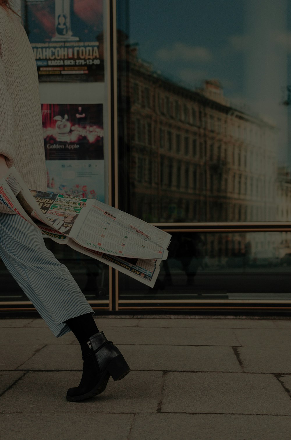 woman walking holding newspaper at the street