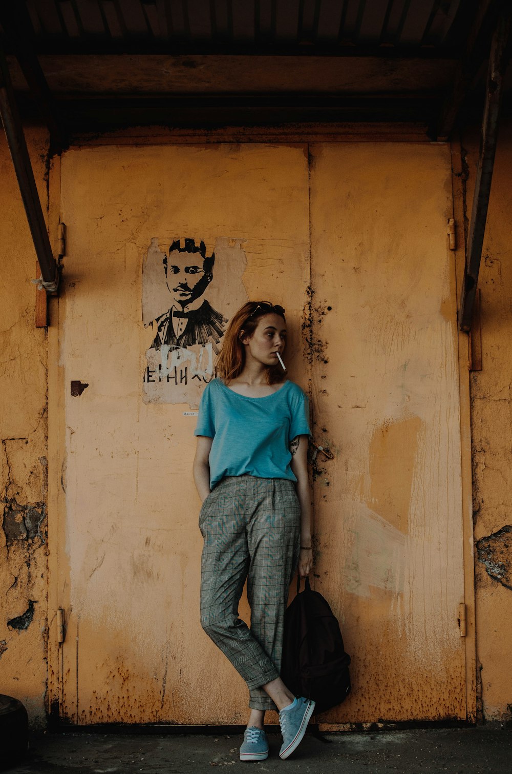 woman lean on wooden wall while holding backpack