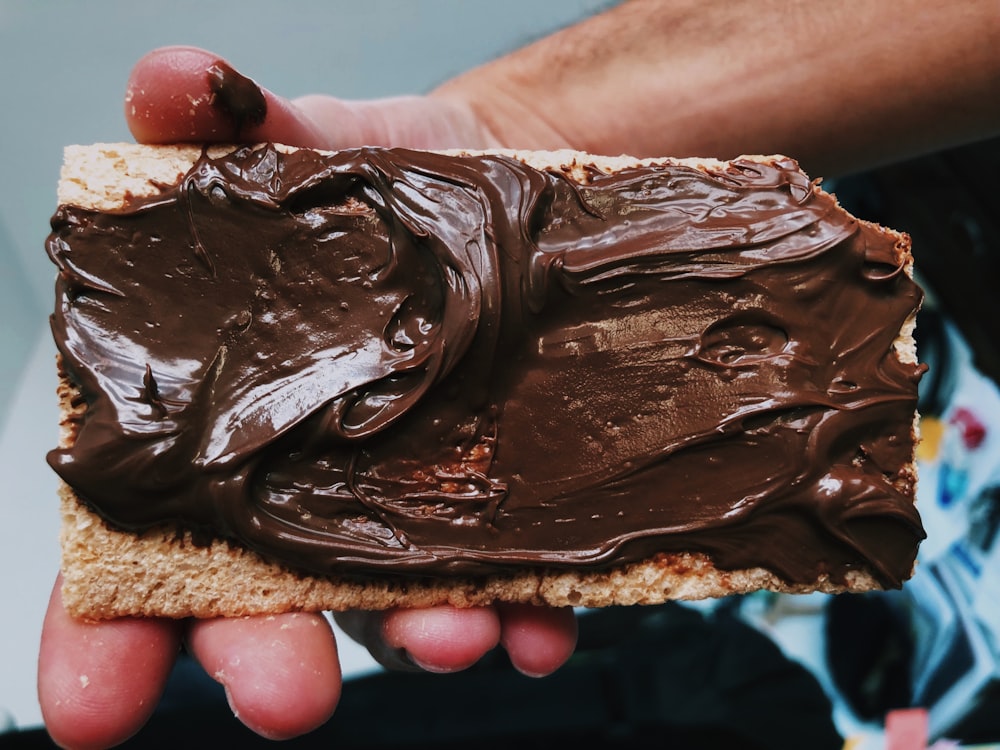 person holding biscuit with nutella