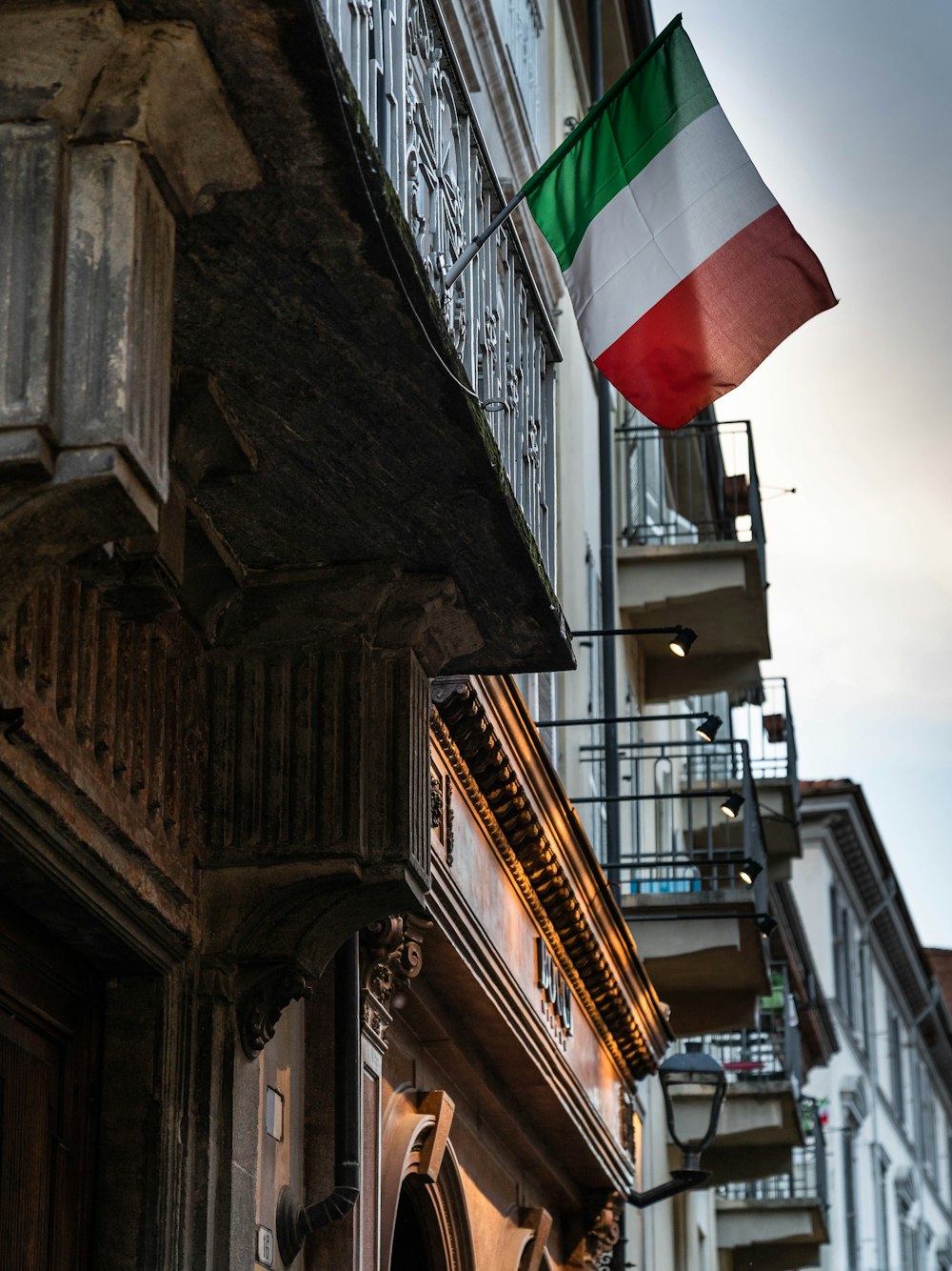 bandeira listrada vermelha, branca e verde no edifício de concreto cinza