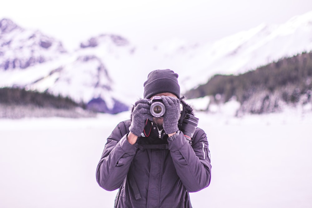 man in black coat holding DSLR camera