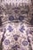 A detailed close-up of an intricately embroidered garment, featuring floral patterns adorned with silver and blue beadwork. The fabric is satin-like, with a lustrous sheen giving it an opulent appearance. The embroidery is rich in detail, combining swirling designs with symmetrical flower motifs.