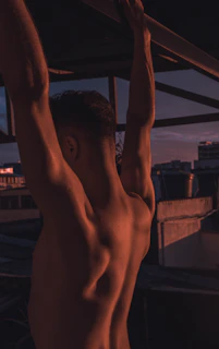 Silhouette of a muscular man stretching against a dark urban backdrop at dawn.