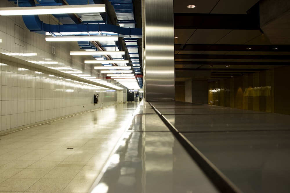 a long hallway with white tile floors and blue and white lights