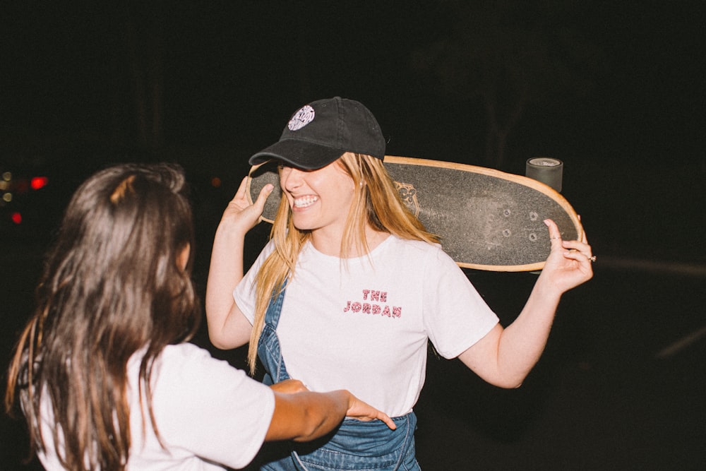 woman wearing white crop-top and blue romper holding black skateboard