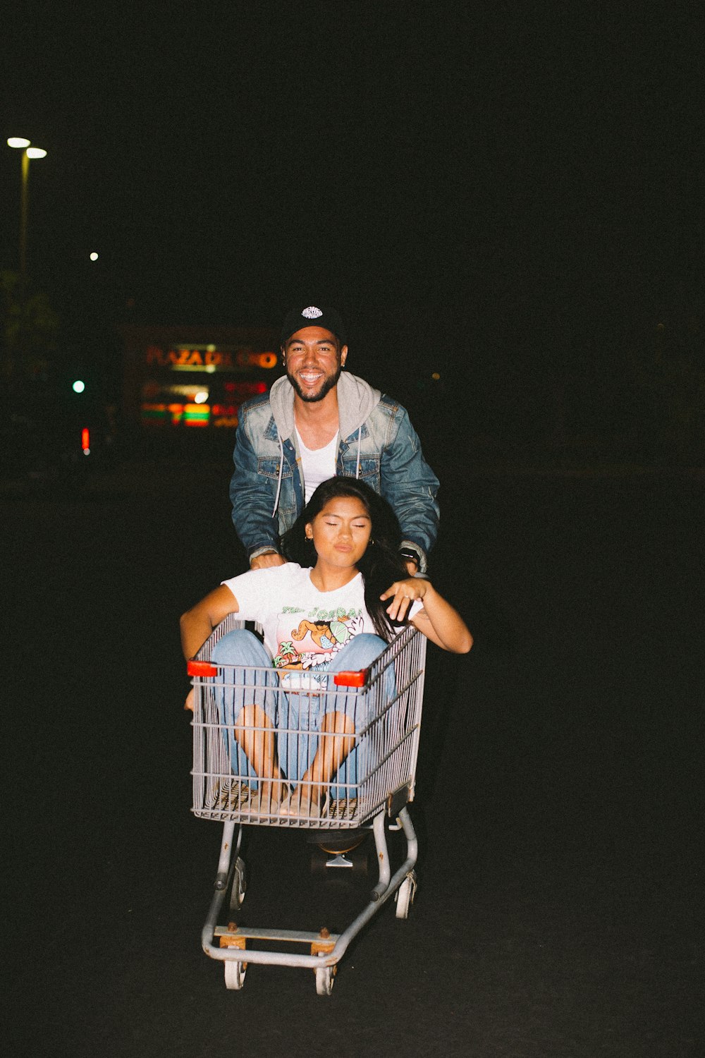 woman in shopping cart pulled by a man