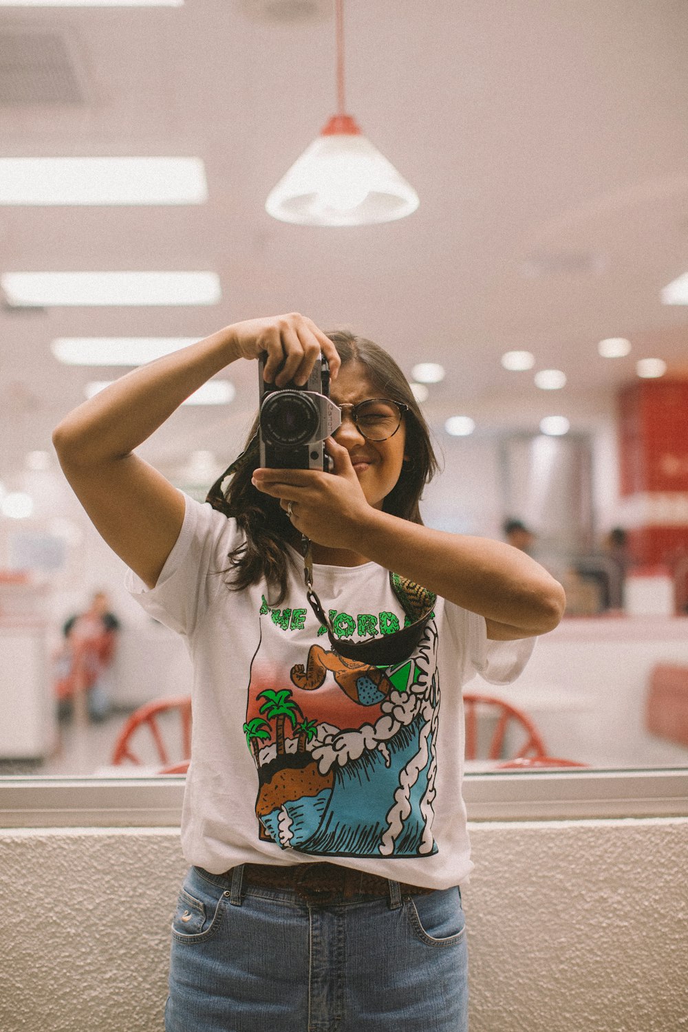 person holding a camera under a white ceiling lamp close-up photography