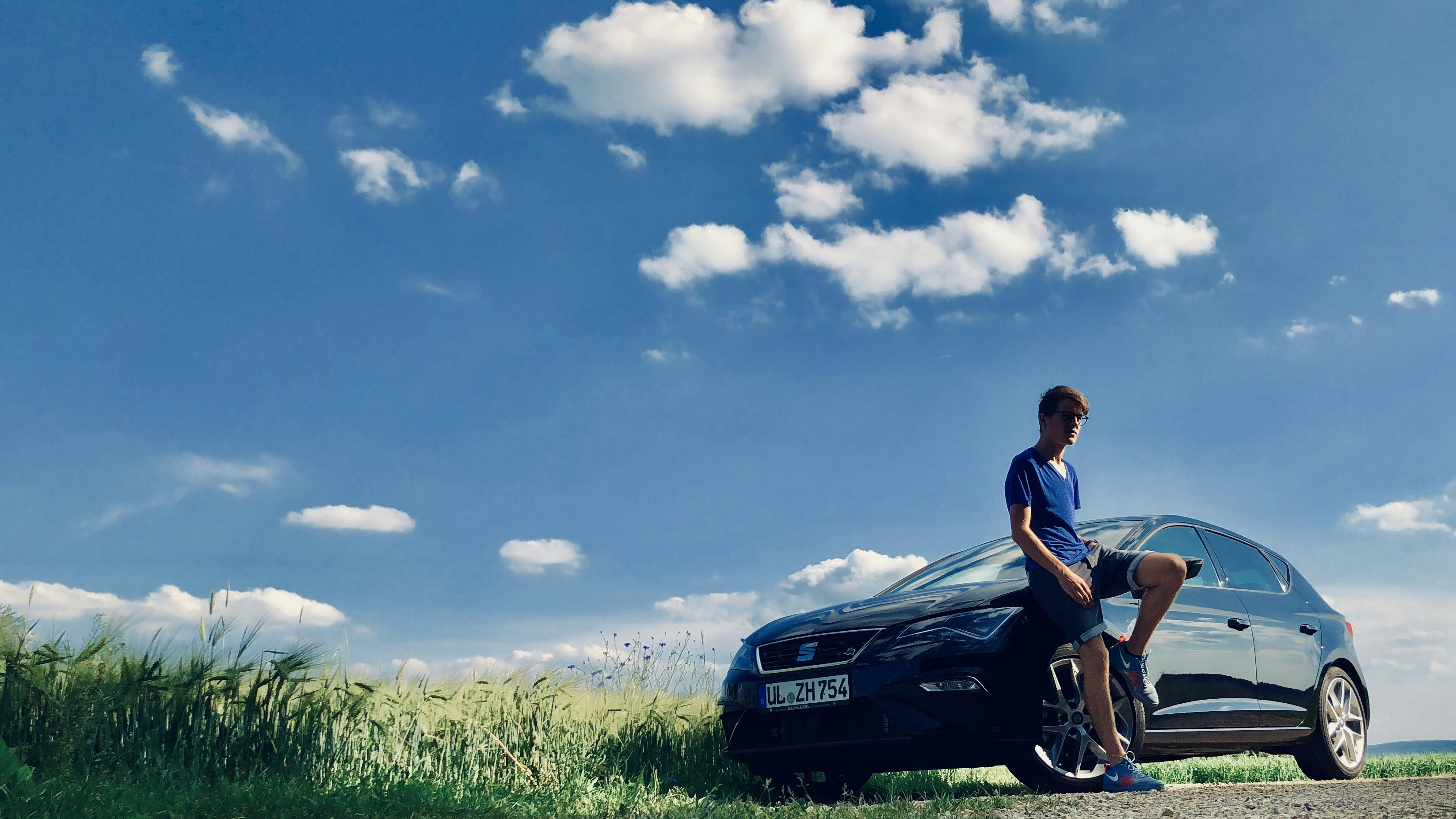 man leaning beside black sedan