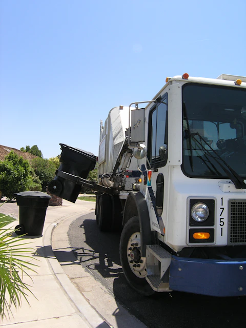 Garbage truck collecting residential trash bins on a neighborhood street