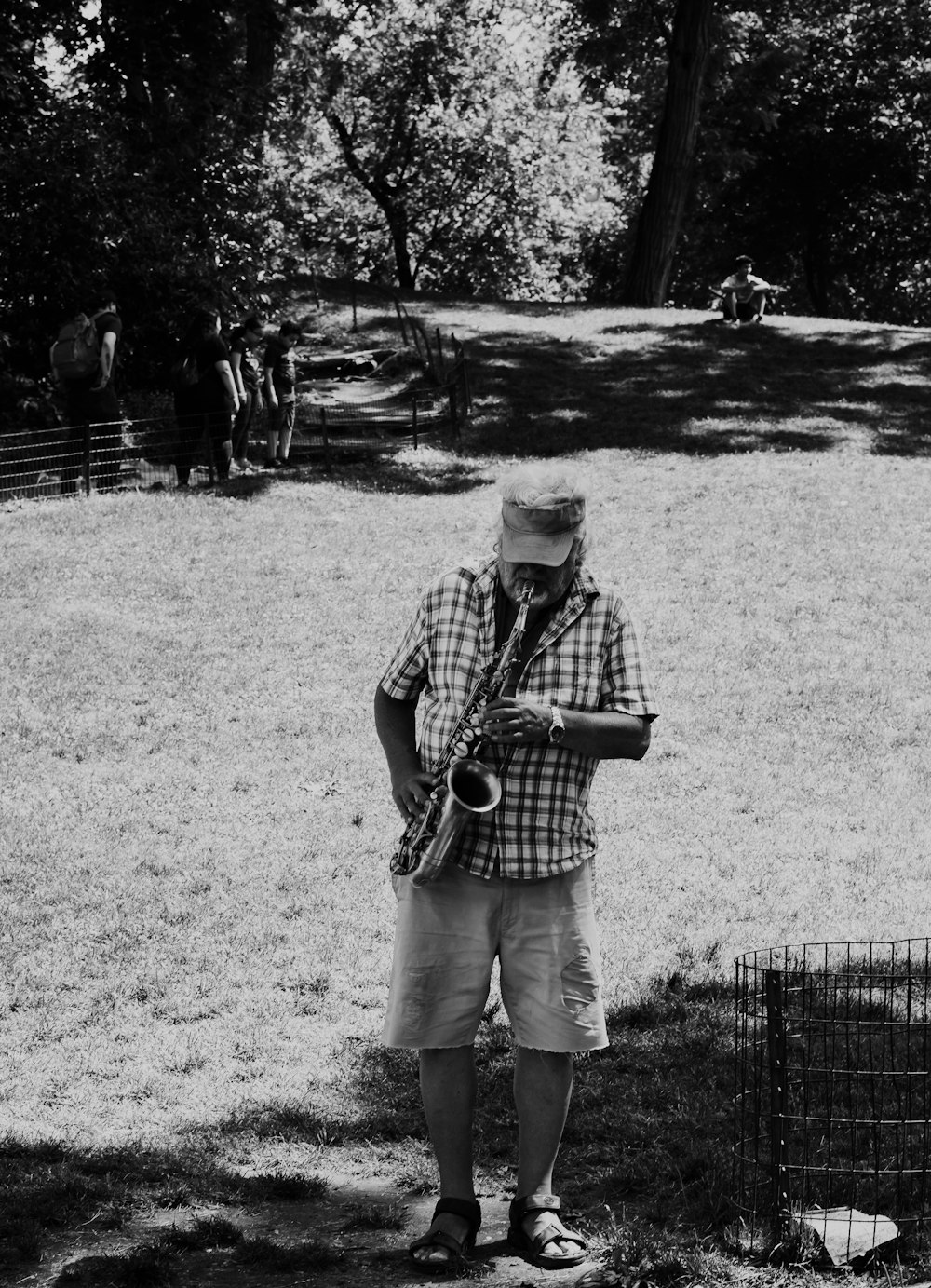 hombre tocando el saxofón en la hierba cerca de los árboles